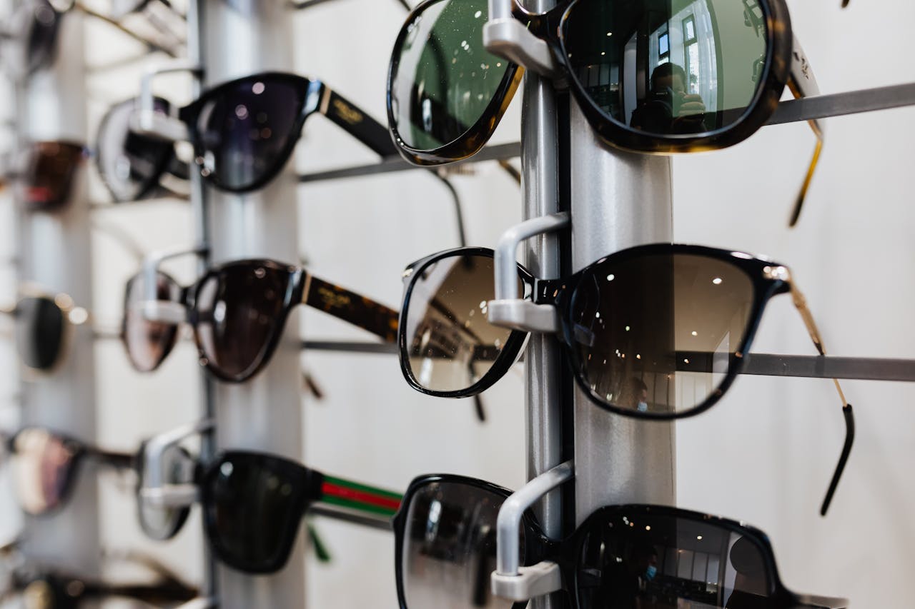 our-story-02 Close-up view of stylish sunglasses displayed on a rack in a retail store.