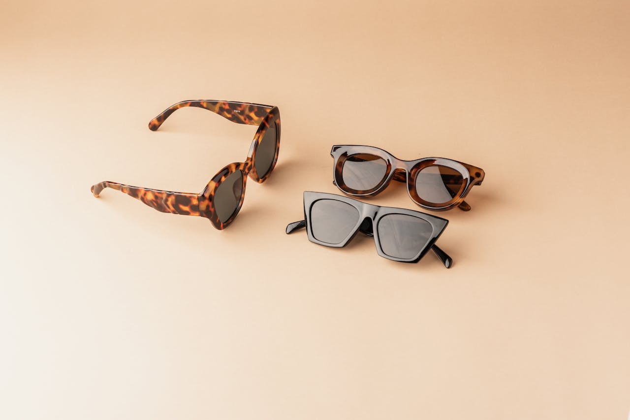 Three stylish sunglasses on a minimalist beige backdrop, showcasing modern eyewear fashion.
